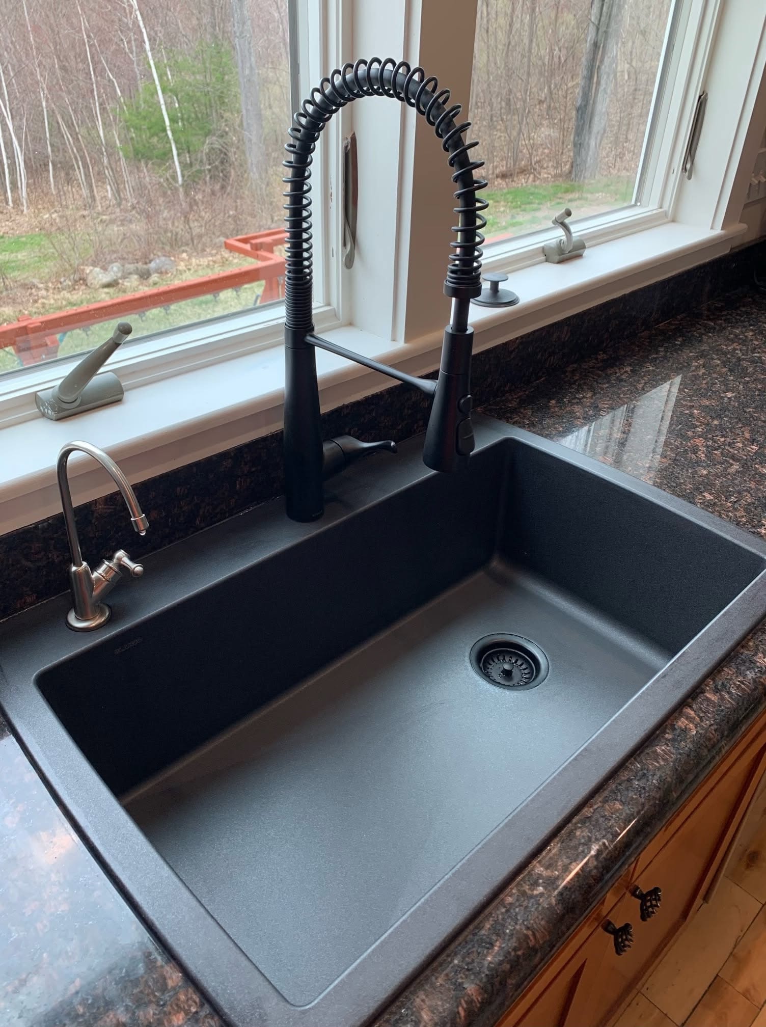 Black kitchen sink with coil faucet on granite countertop